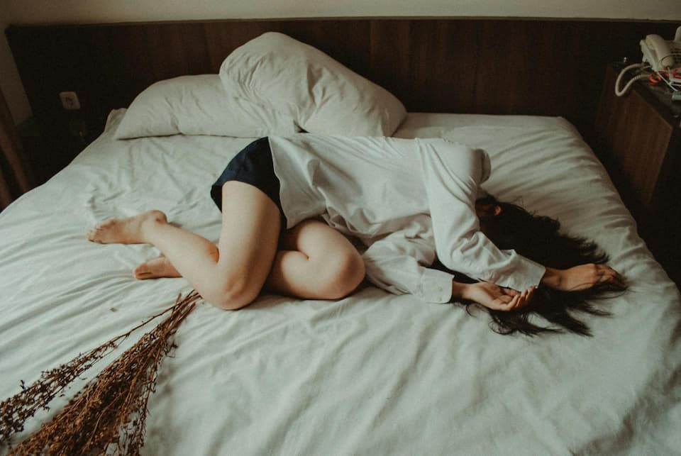 Exhausted woman lying curled up on a bed, symbolizing parental burnout